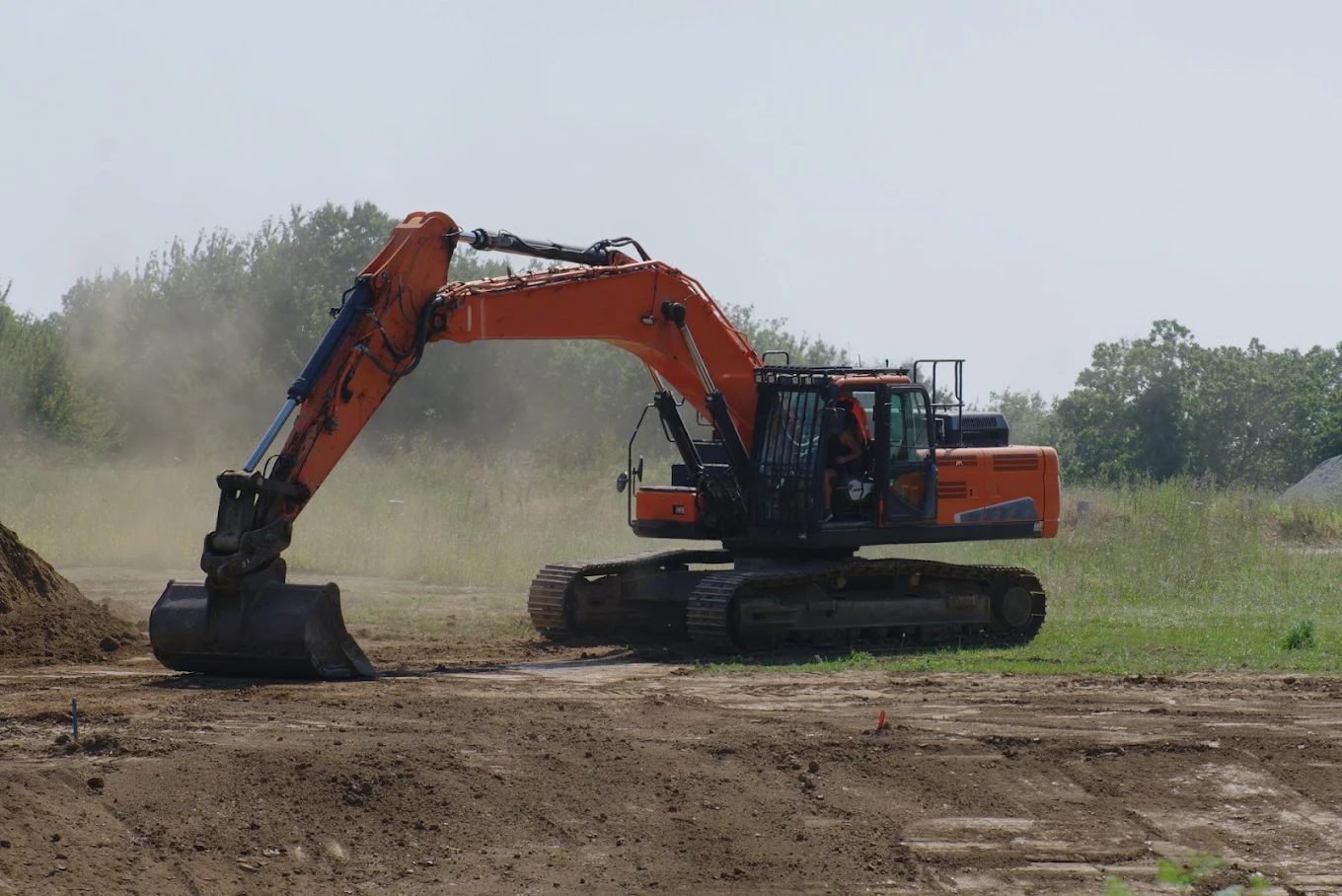 Orange excavator digging on a graded dirt pad