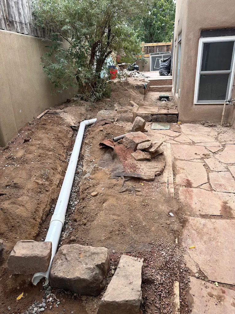 Drainage trench with pipe beside a stone walkway