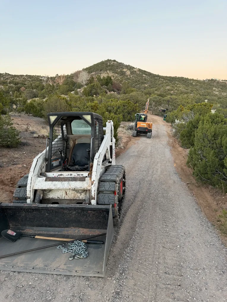Skid steer and excavator on a graded access road